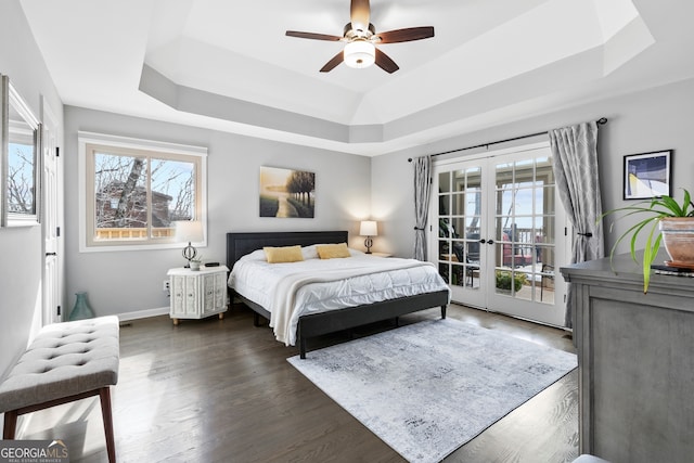 bedroom featuring access to exterior, a tray ceiling, dark wood finished floors, and french doors