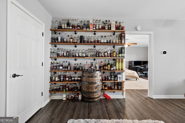 bar with a dry bar, baseboards, and dark wood-type flooring