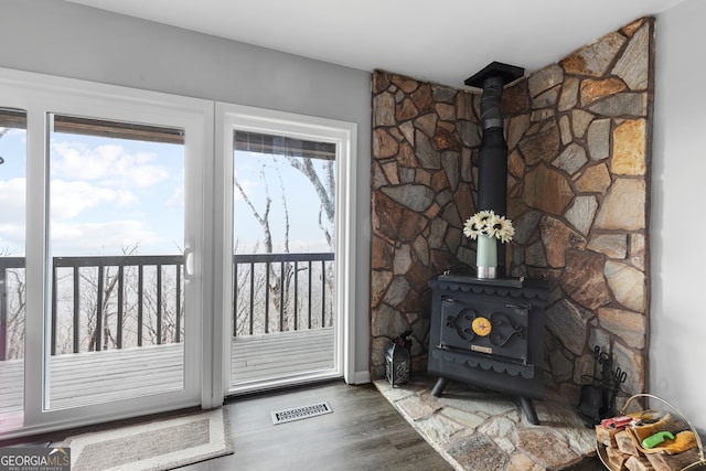 doorway with visible vents, wood finished floors, and a wood stove