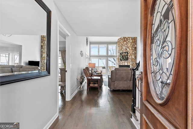 foyer entrance with dark wood-style floors, a fireplace, and baseboards