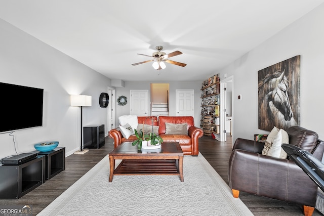 living area featuring a ceiling fan, dark wood finished floors, and baseboards