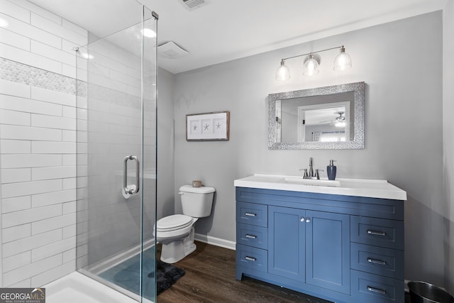 full bath featuring toilet, a stall shower, vanity, wood finished floors, and baseboards