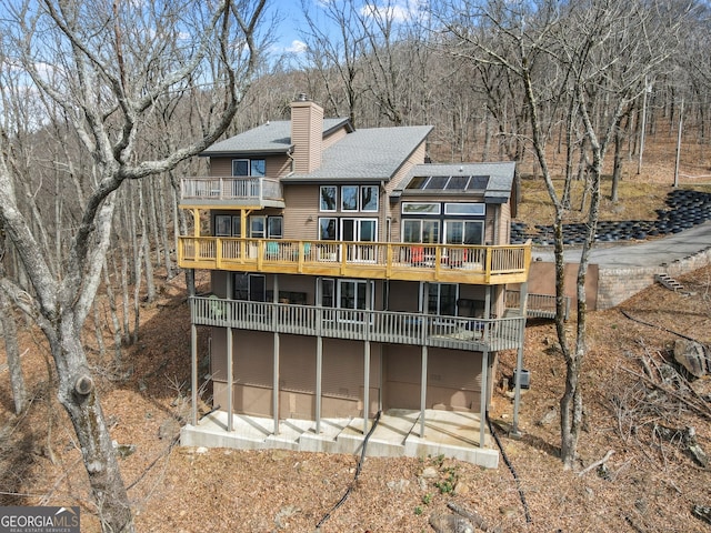 back of property featuring a chimney and roof with shingles