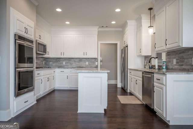 kitchen featuring stainless steel appliances, hanging light fixtures, a center island, and white cabinets