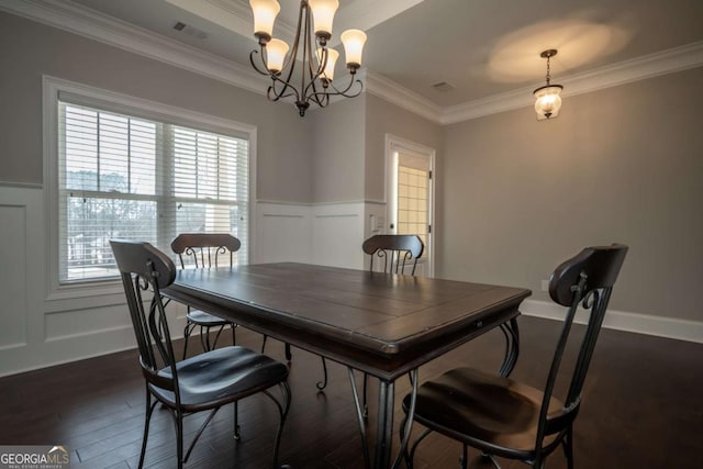 dining room with a notable chandelier, visible vents, a decorative wall, dark wood-type flooring, and ornamental molding