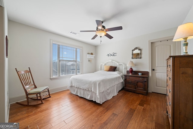 bedroom featuring ceiling fan, dark wood-style flooring, visible vents, and baseboards