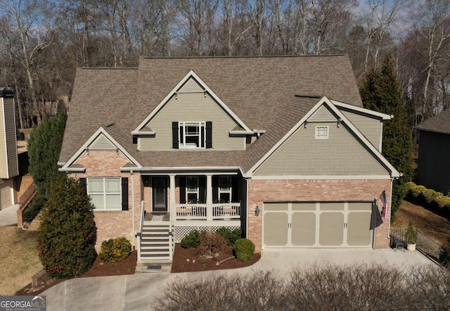 view of front of house featuring a garage, concrete driveway, covered porch, stairs, and brick siding