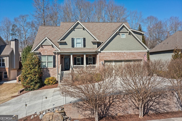 craftsman house featuring covered porch, brick siding, and an attached garage