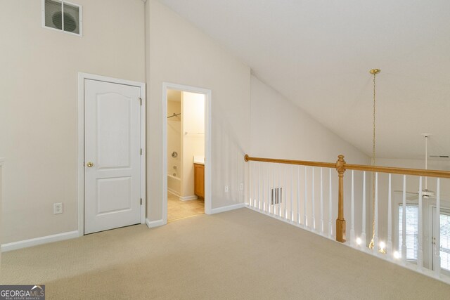 additional living space with vaulted ceiling, baseboards, visible vents, and light carpet