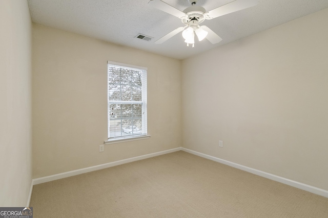 spare room featuring light carpet, visible vents, a ceiling fan, and baseboards