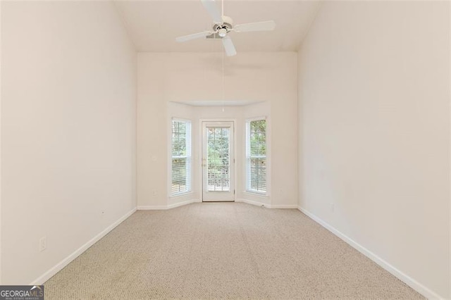 carpeted spare room with ceiling fan and baseboards