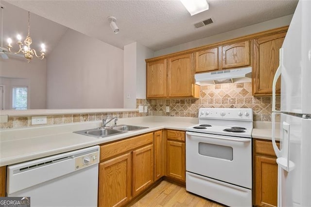 kitchen featuring visible vents, under cabinet range hood, light countertops, white appliances, and a sink