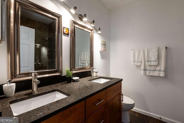 bathroom with a sink, a tile shower, toilet, and double vanity