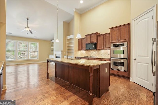 kitchen with light stone counters, a center island, double oven, a kitchen bar, and pendant lighting