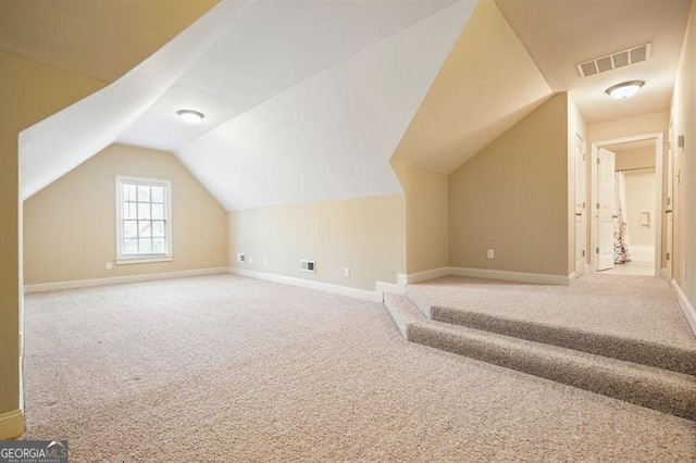 additional living space with light carpet, lofted ceiling, visible vents, and baseboards