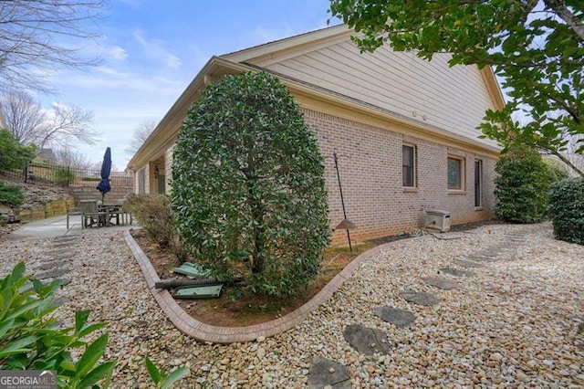 view of home's exterior featuring brick siding, a patio area, and fence