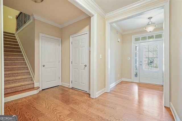 entrance foyer featuring baseboards, ornamental molding, stairway, and light wood-style floors