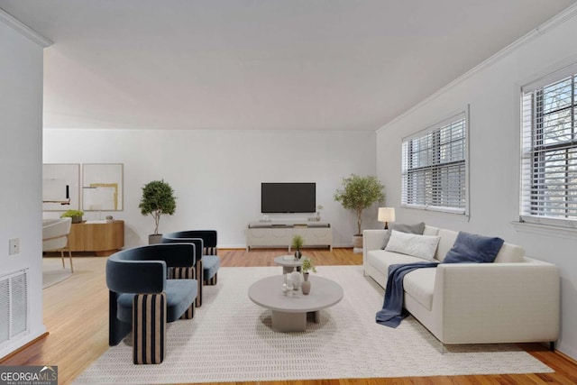 living area with visible vents, wood finished floors, and ornamental molding