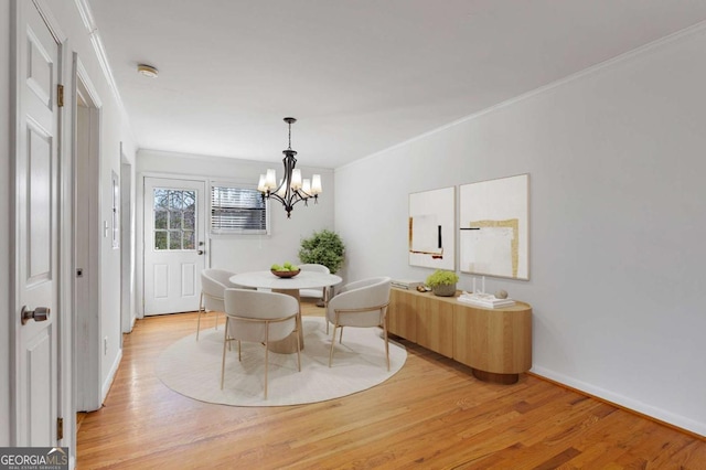 dining space with light wood-type flooring, crown molding, baseboards, and an inviting chandelier