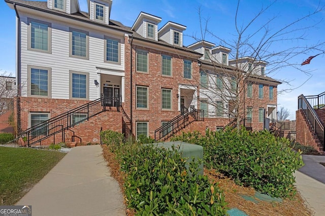 view of front facade featuring brick siding and stairway