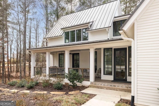 entrance to property with a porch, a standing seam roof, and metal roof