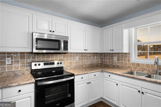 kitchen featuring tasteful backsplash, white cabinets, appliances with stainless steel finishes, a textured ceiling, and a sink