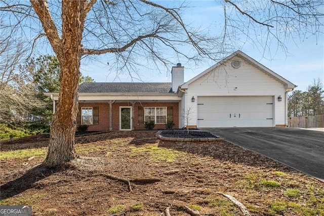 single story home featuring a garage, driveway, a chimney, and brick siding