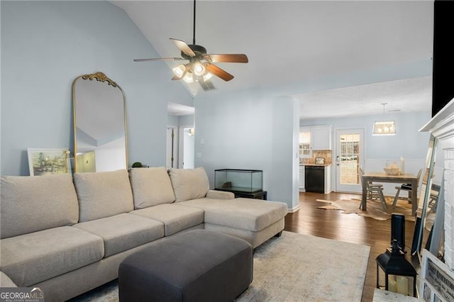 living room featuring ceiling fan, vaulted ceiling, a fireplace, and wood finished floors