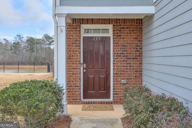 property entrance with brick siding and fence