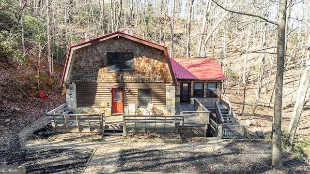 chalet / cabin featuring a deck, metal roof, a gambrel roof, stairway, and a wooded view