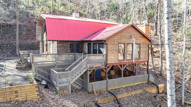 back of property featuring a deck, metal roof, stairway, and a chimney