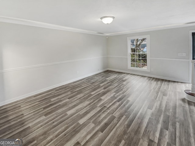 empty room with ornamental molding, dark wood finished floors, and baseboards