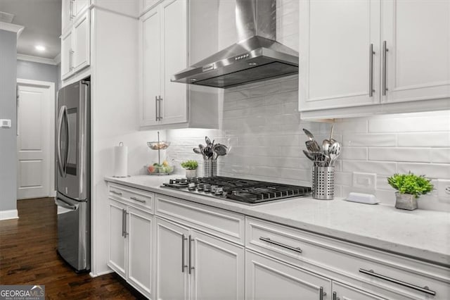 kitchen featuring dark wood-style floors, stainless steel appliances, decorative backsplash, white cabinets, and wall chimney exhaust hood