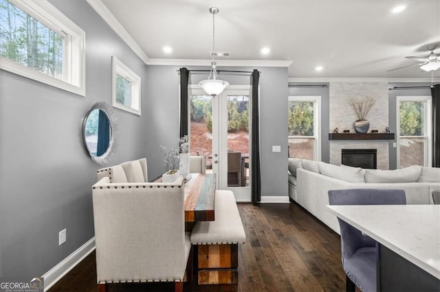 dining room featuring ornamental molding, dark wood-style flooring, a fireplace, and baseboards