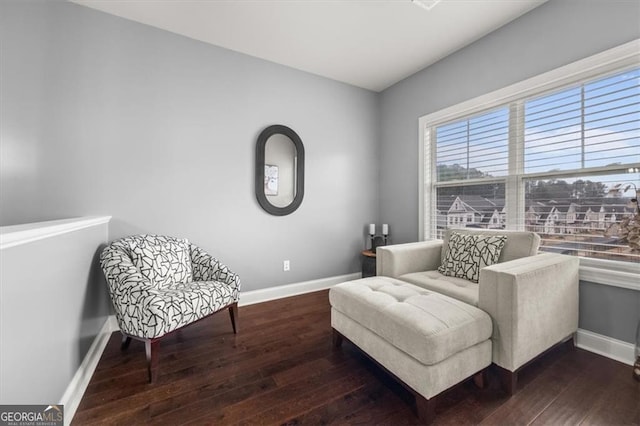 sitting room with dark wood-type flooring and baseboards