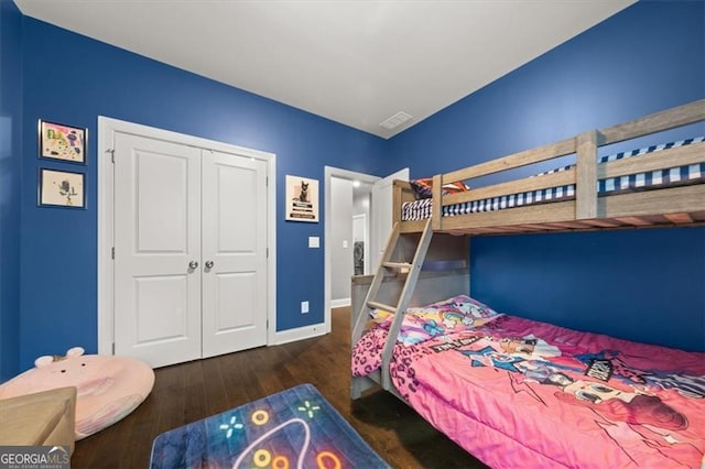 bedroom with dark wood-style flooring, a closet, visible vents, and baseboards