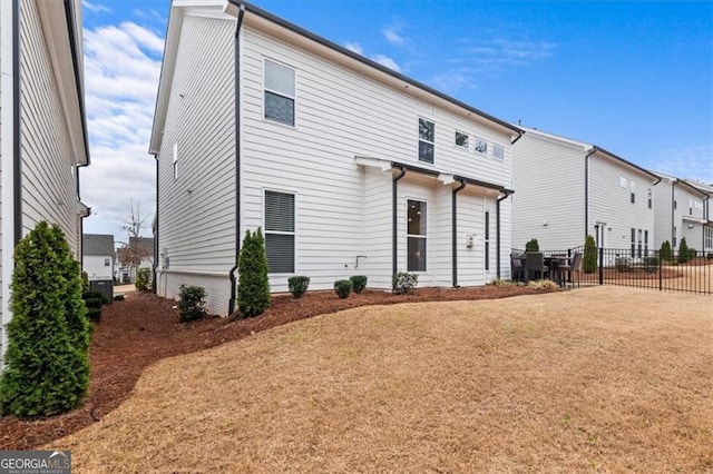 back of property featuring a lawn and fence