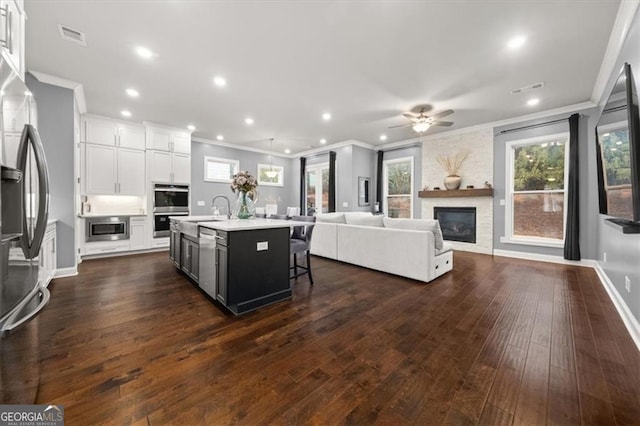 kitchen with a center island with sink, a breakfast bar, open floor plan, stainless steel appliances, and light countertops