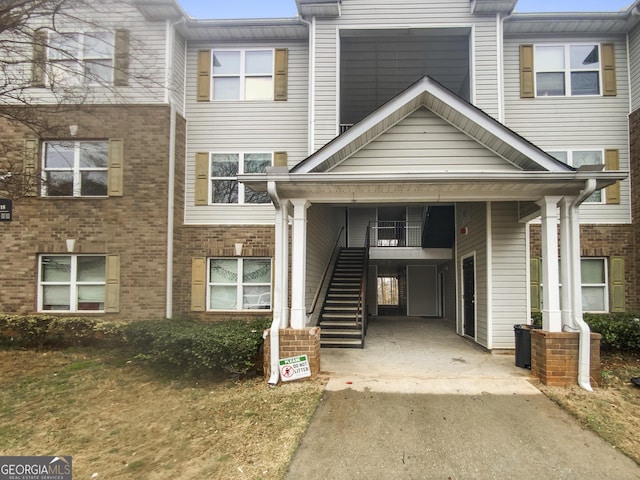 view of front of home featuring concrete driveway, brick siding, and stairway