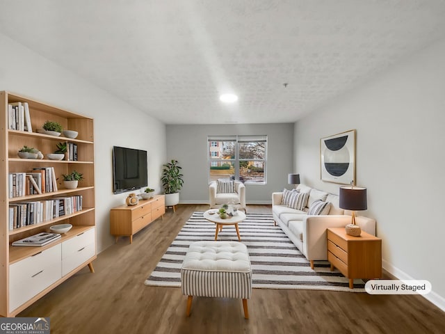 living area with a textured ceiling, wood finished floors, and baseboards