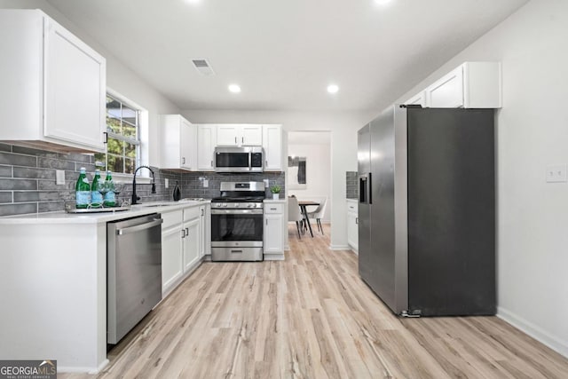 kitchen featuring light countertops, visible vents, appliances with stainless steel finishes, white cabinetry, and a sink