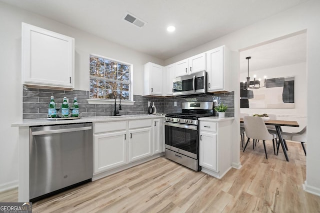 kitchen featuring white cabinets, appliances with stainless steel finishes, light countertops, and decorative light fixtures