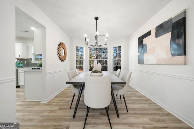 dining area with baseboards, light wood finished floors, and an inviting chandelier