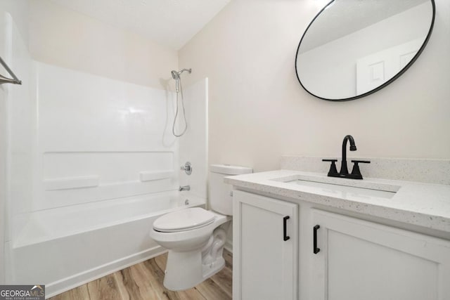 bathroom featuring toilet, wood finished floors, shower / tub combination, and vanity