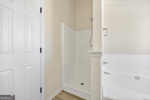 bathroom featuring wood finished floors, a shower stall, and a bath