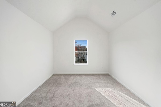 interior space featuring vaulted ceiling, baseboards, visible vents, and light colored carpet