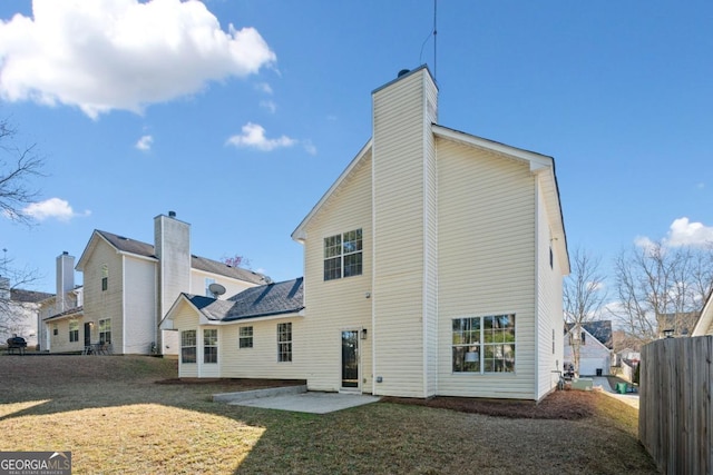 back of house with a patio area, a lawn, and a chimney