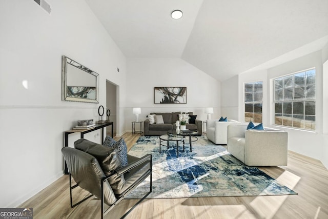 living room featuring light wood-style floors, visible vents, and vaulted ceiling