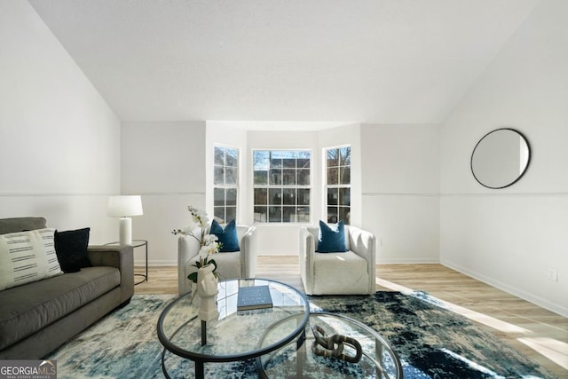 living room featuring lofted ceiling, light wood-type flooring, and baseboards