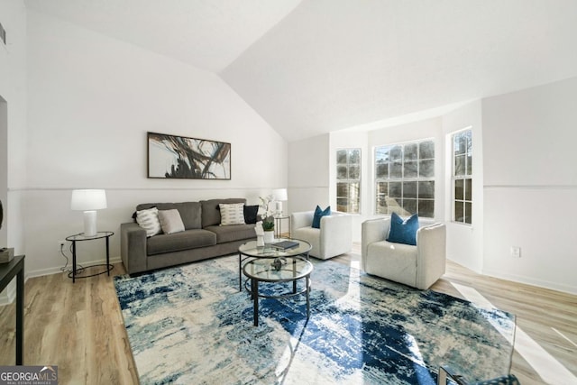 living area with lofted ceiling, baseboards, and wood finished floors